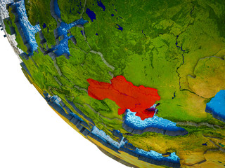Ukraine on model of Earth with country borders and blue oceans with waves.