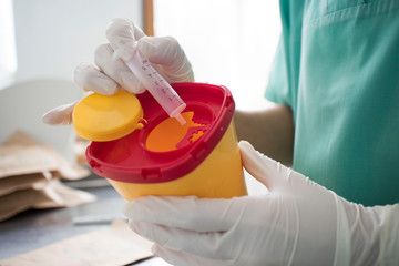 Doctor put syringe in red disposal boxes. concept of pandemic, coronavirus, virus, disinfection, panic.