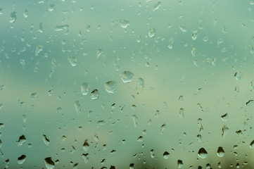 raindrops on window glass on background of cloudy sky