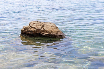 Solitary rock boulder in the sea water horizontal right