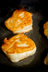 Cooking pancakes on a black pan with oil