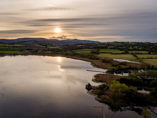 Aerial panoramic view of a beautiful natural lake in Brecon Beacons surrounded by rural farmland (Llangorse Lake, Wales)