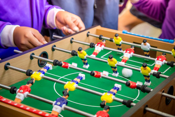 Kick off strike in table football game. Young people playing foosball table game.