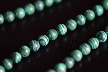 Malachite stone beads necklace on a dark background close up