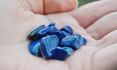 Pile of lapis lazuli stones with inclusions of golden pyrite in human hand. Concept of lithotherapy.