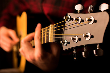 Man's hands playing acoustic guitar, close-up