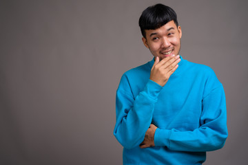 Fototapeta premium Portrait of young Asian man against gray background