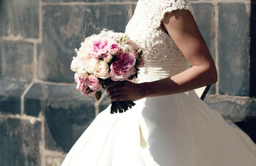 Woman is holding beautiful wedding bouquet in her hands.