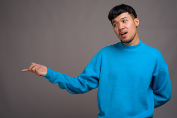 Portrait of young Asian man against gray background