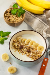 Granola. Granola with yogurt, chocolate and banana on a white stone table.