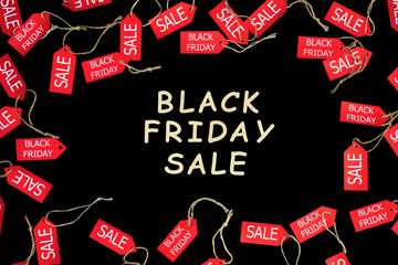 Red shopping sale discount labels on black isolated background with wooden text "Black Friday Sale". Fashion black friday holiday, sale and discount in shopping mall or cloth store concept