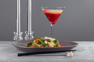 Poke with beef and rice on a beautiful plate with candles and a glass of drink. Hawaiian cuisine.