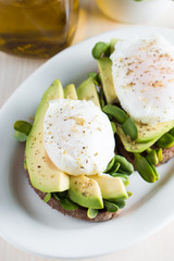 Avocado toast, cherry tomato on wooden background. Breakfast with toast avocado, vegetarian food, healthy diet concept. Healthy sandwich with avocado and poached eggs.
