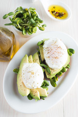 Avocado toast, cherry tomato on wooden background. Breakfast with toast avocado, vegetarian food, healthy diet concept. Healthy sandwich with avocado and poached eggs.