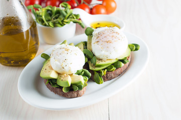 Avocado toast, cherry tomato on wooden background. Breakfast with toast avocado, vegetarian food, healthy diet concept. Healthy sandwich with avocado and poached eggs.