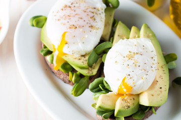 Avocado toast, cherry tomato on wooden background. Breakfast with toast avocado, vegetarian food, healthy diet concept. Healthy sandwich with avocado and poached eggs.