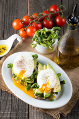 Avocado toast, cherry tomato on wooden background. Breakfast with toast avocado, vegetarian food, healthy diet concept. Healthy sandwich with avocado and poached eggs.