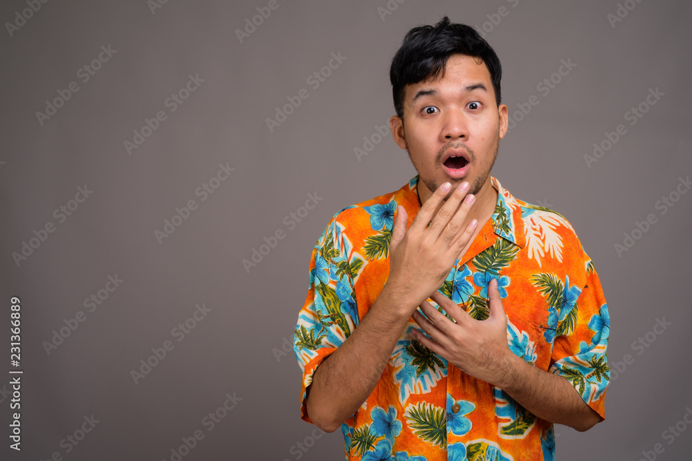 Sticker Young Asian tourist man ready for vacation against gray backgrou