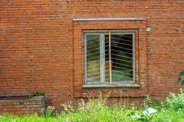 The barred window in the brick wall of the house