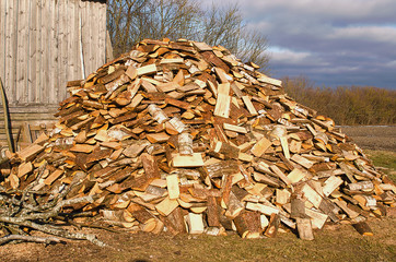 Pile of chopped firewood lies near the fence at the house