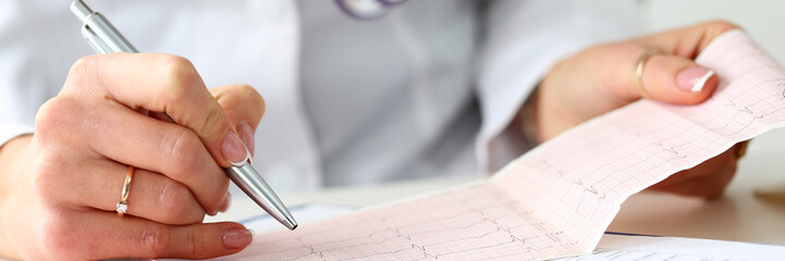 Doctor hands with cardiogram chart on clipboard pad