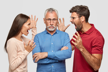 Guilty grey haired bearded senior man keeps arms folded, hears approaches from young colleagues who...