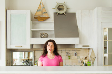 Housewives, emotions and people concept - Surprised young woman in the kitchen at home
