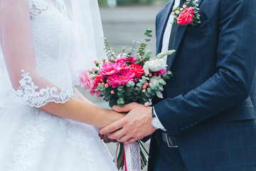 Close-up of the groom holding the bride by the hands