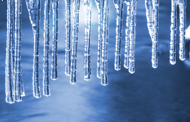 Transparent icicles hang above the surface of the water.