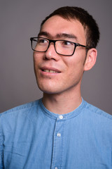 Portrait of young Asian businessman against gray background