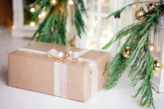 Christmas box over white wooden background with lights.  New Year's decoration with  fir branches in white tones.