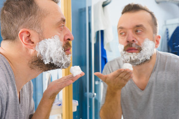 Guy shaving his beard in bathroom