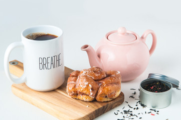 pink tea pot, tea leaves and mug with a donut