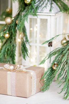 Christmas box and lantern over white wooden background with lights.  New Year's decoration with  fir branches in white tones.