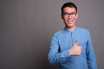 Portrait of young Asian businessman against gray background