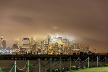 Manhattan skyline during rain, clouds sky.    