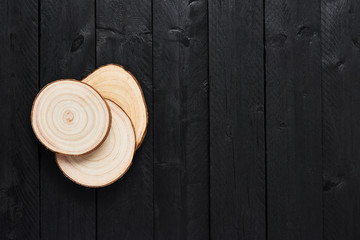 Top view of transverse wooden saw cuts on black wooden table with copy space.