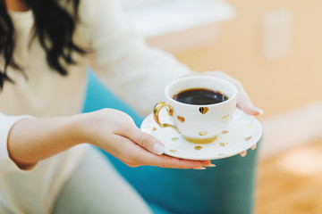 Young woman holding a cup of coffee in a chair in her home