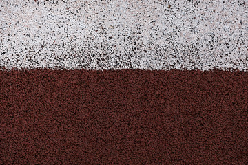 Fototapeta premium Running track and field texture background. Background of running track field surface closeup macro photo with white line.