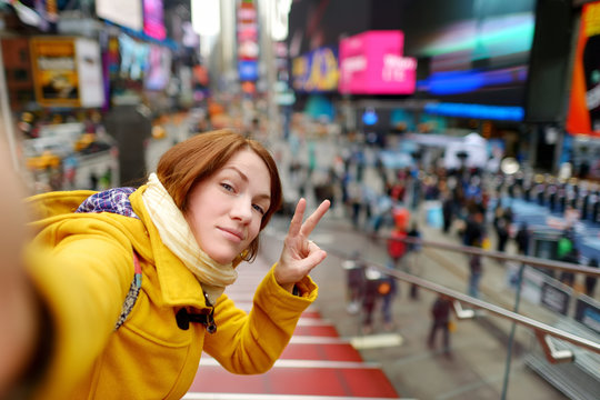 Happy young woman tourist sightseeing at Times Square in New York City. Female traveler enjoying view of downtown Manhattan.