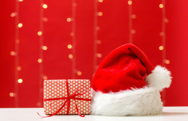 Santa hat with a gift box on a shiny light red background