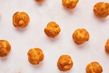 Close up of assorted fresh cream puff cakes on rose background. Top view.