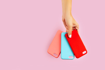 hands holding colorful smartphone cases. Pink Background