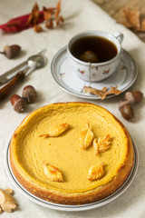 Traditional American pumpkin homemade cake, decorated with cookies on a background of pumpkins and autumn leaves.