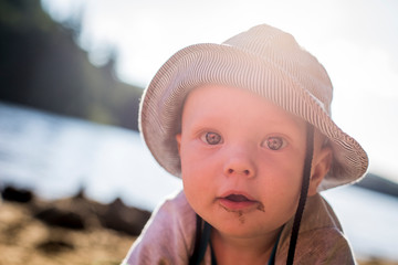Magnifique garçon jouant sur la plage regardant la caméra. Jeune enfant jouant au soleil l'été.