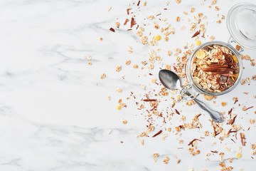 Top view of healthy breakfast. Jar of healthy yogurt with strawberry sauce, oat and chocolate on white marble table. Close up with copy space.