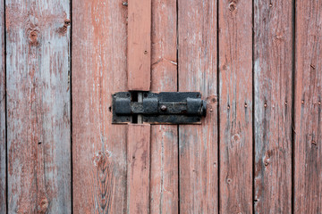 The red wooden door of an old house with a lock and bolt. Door bolt photos.