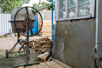 Concrete mixer at construction site and pine wooden stack.