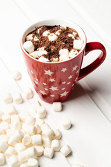 Hot cocoa in a red mug decorated with white stars and a bunch of marshmallows