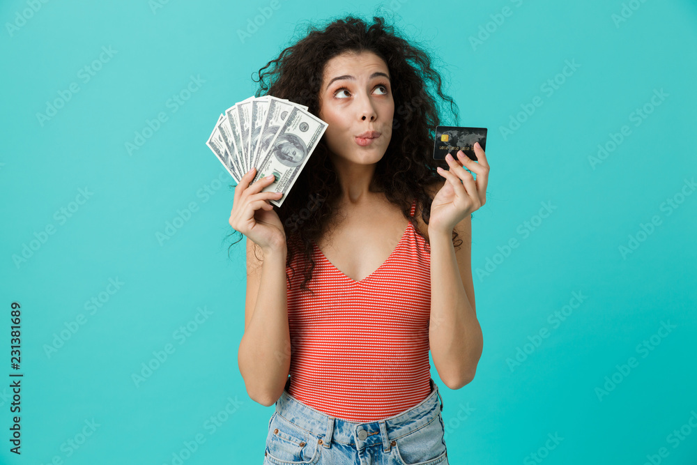 Sticker Image of young woman 20s wearing casual clothing holding fan of dollar money and credit card, standing isolated over blue background